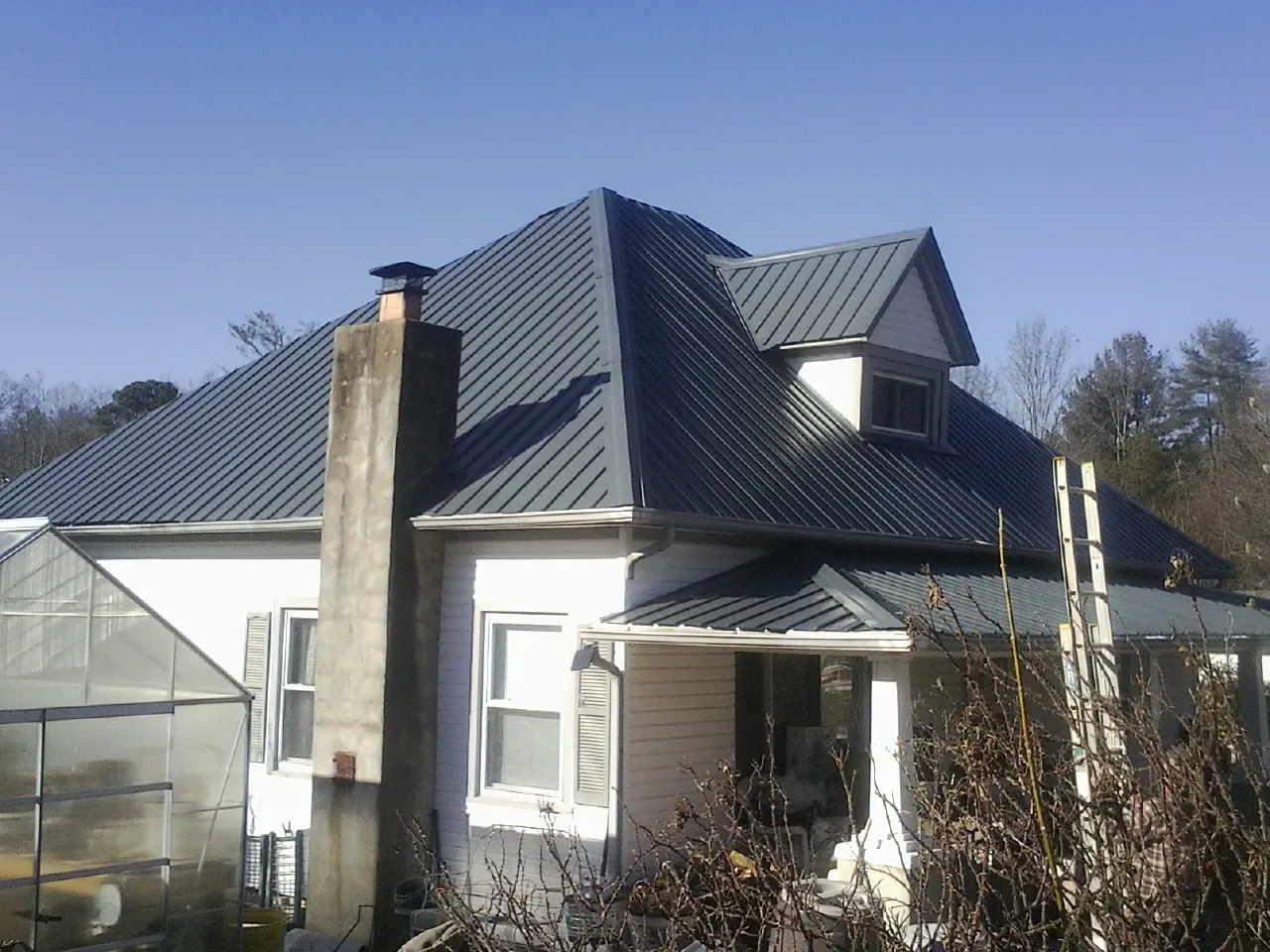 Dark blue standing seam metal roof on a white farmhouse with dormer — Slate & Tile Roof Repair by Roofing Brothers in Crane Hill