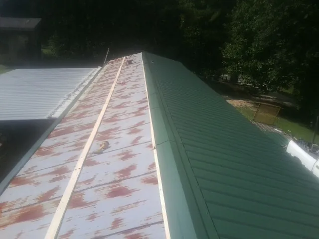 Old rusted panels beside newly installed green metal roofing — Wind Damage Roof Repair by Roofing Brothers in Crane Hill