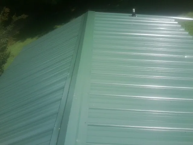 New green metal panels meeting at the ridge of a roof — Flat Roof Repair work by our crew in Crane Hill