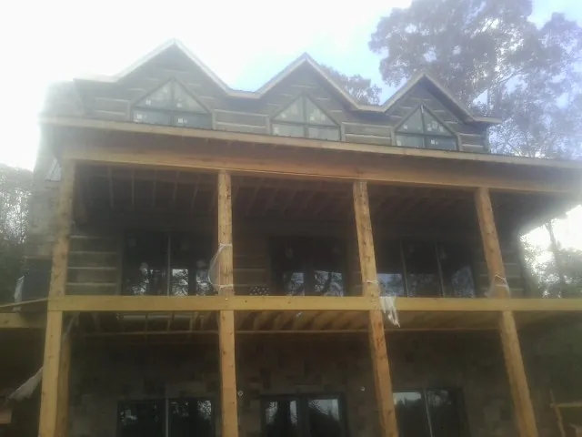 Dormers and porch framing on a large log home under construction — Roof Coating work by our crew in Crane Hill