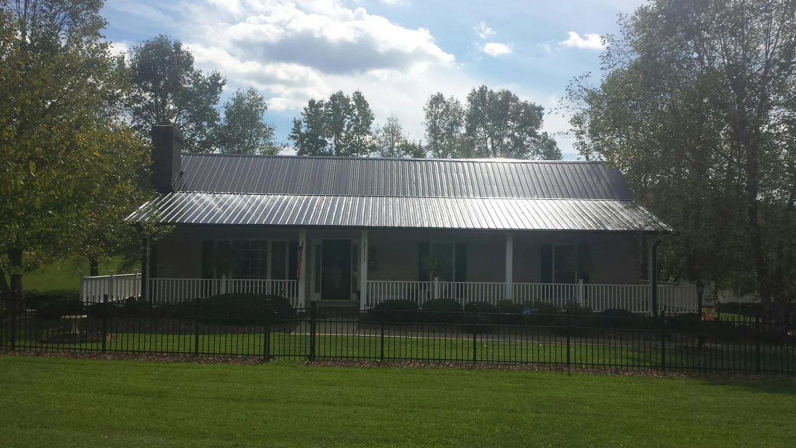 Gray metal roof on a brick ranch with a full width front porch — Gutter Guard Installation work by our crew in Crane Hill