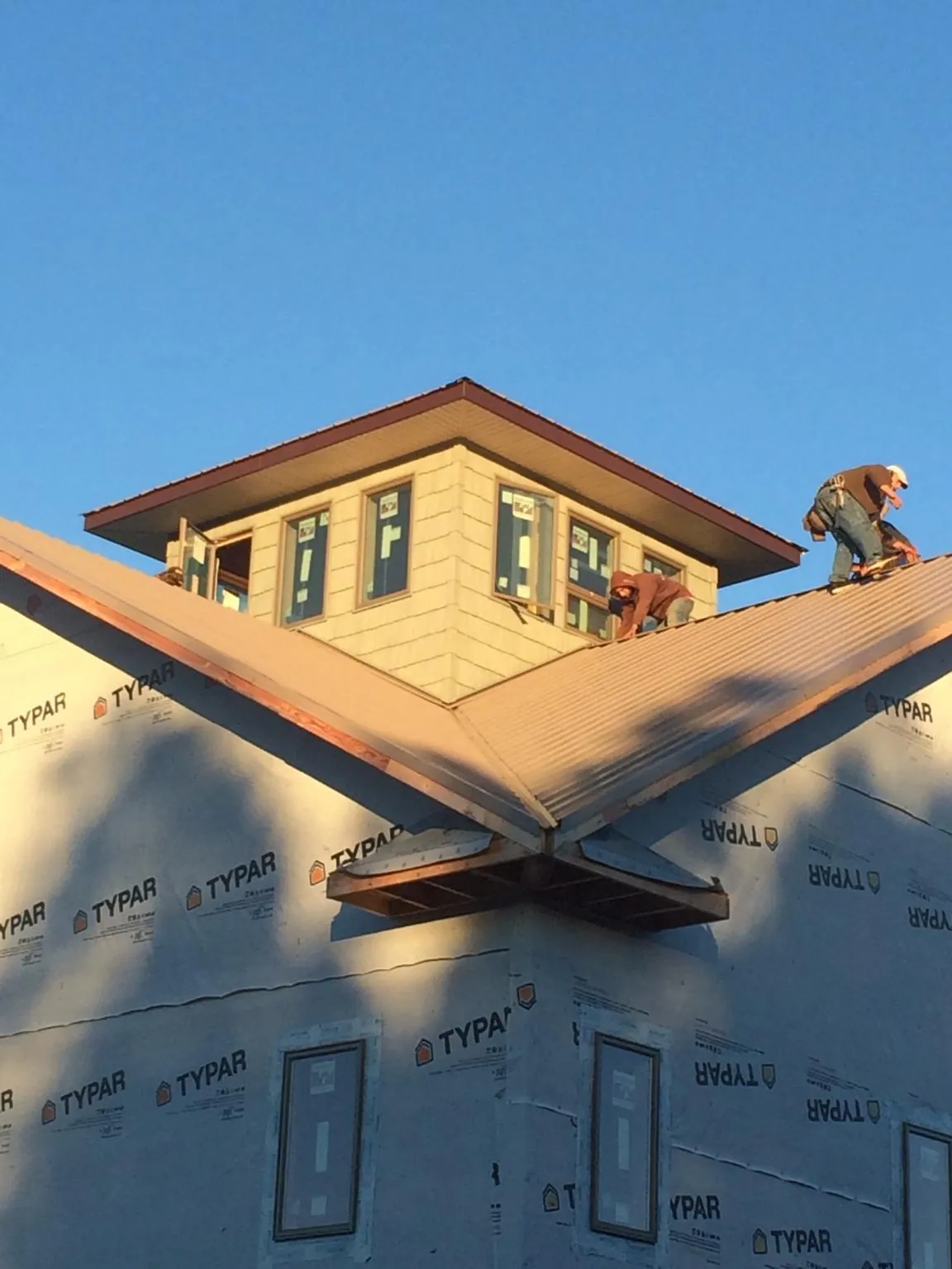 Roofers working around a rooftop cupola on a new metal roof at sunset — Roof Waterproofing in Crane Hill by Roofing Brothers